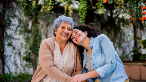 Woman resting her head on elderly woman's shoulder.