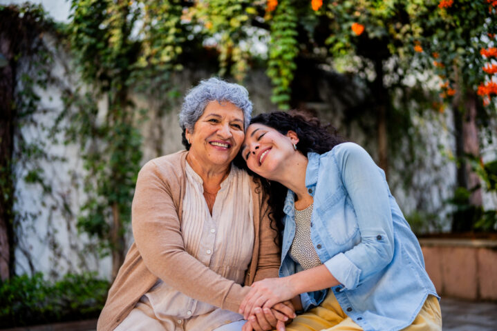 Woman resting her head on elderly woman's shoulder.